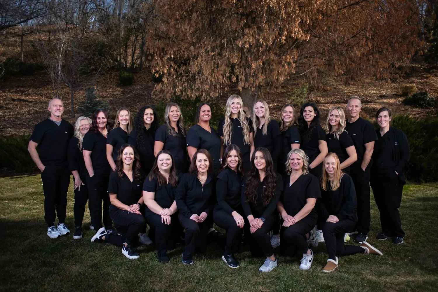 Dental team members wearing black scrubs posing together outdoors.